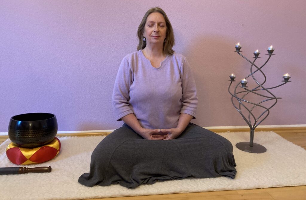 Hilkea Knies, im meditativen Sitz, mit Klangschale und Leuchter. Vorbereitung für Stimme und Meditation